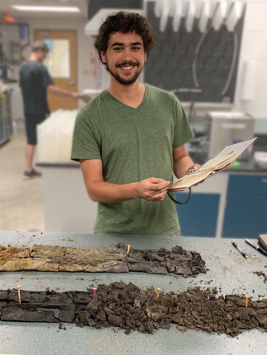 A student poses for a photo in the Sediment Lab