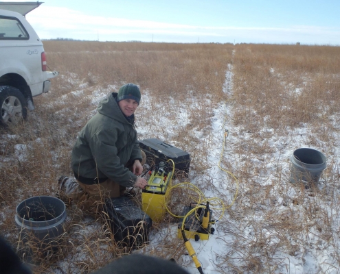 A researcher setting up equipment in a snowy field