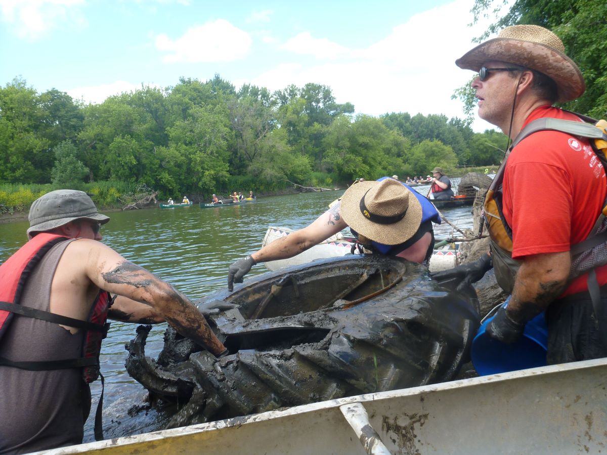 Ryan Clark scooping mud out of a tractor tire with the help of volunteers Jeremy Davis and Dan Ceynar.