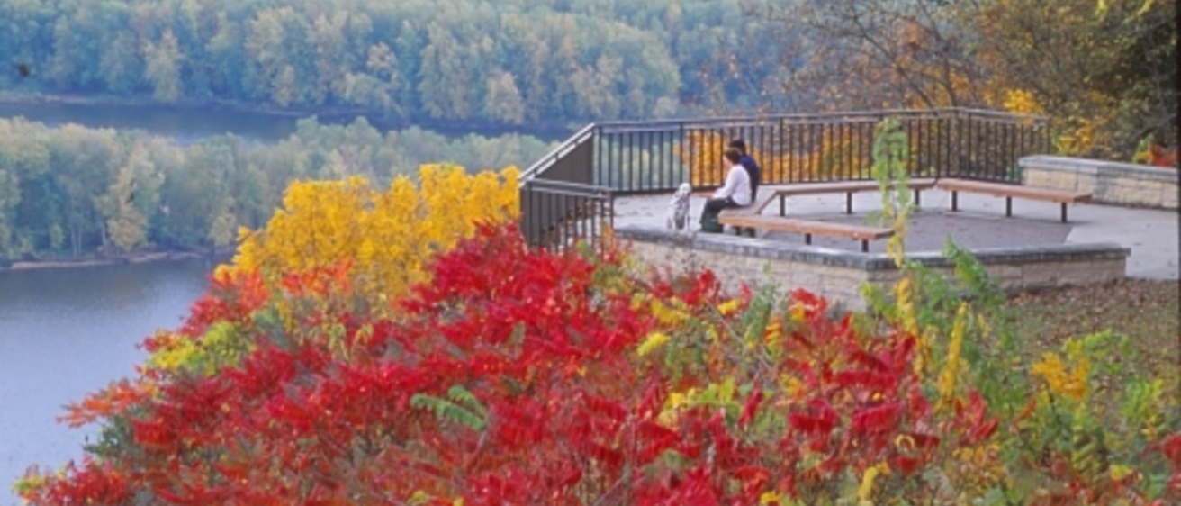 People sitting on an overlook among fall foliage