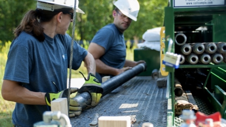 Two people handling drilling equipment